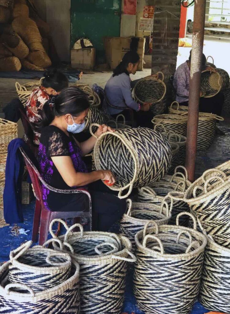 An image showcasing Asia Hands' factory, where a group of women is busy removing and cleaning seagrass baskets
